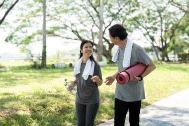 Yogadan sonra dışarıda yürüyen neşeli yaşlı bir çift sağlıklı bir yaşam tarzını somutlaştırıyor ve gülücüklerini ve bağlantılarını paylaşıyor..