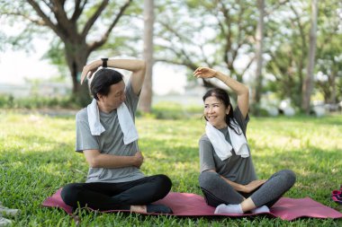 Üst düzey bir çift parkta yoga pratiği yapıyor. Paylaştıkları yolculukta refah ve neşe gösteriyorlar..