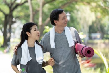 Çevresi doğa ile çevrili, parkta yoga yaparken mutlu anları paylaşan aktif bir çift..