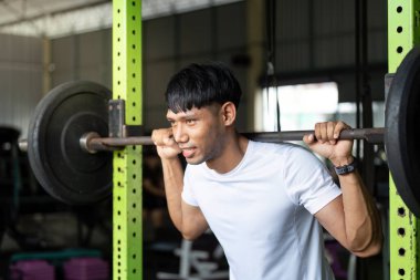 Kendini adamış bir birey vücut geliştirme merkezinde ağırlık kaldırmaya ve ağırlık kaldırmaya odaklanır..