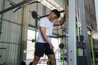 Bir adam sağlık yolculuğunun bir parçası olarak güç antrenmanına odaklanarak spor aletleri üzerinde çaba sarf eder..