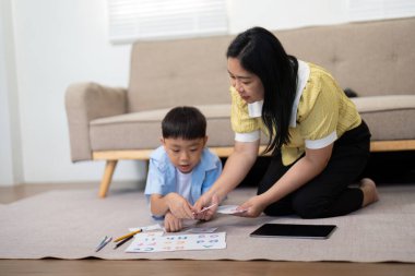 Bir anne oğluna eğitim materyallerinde yardım eder, yetiştirme yurdunda öğrenme sevgisini teşvik eder..