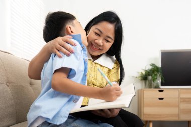 Bir anne ve oğlu evde birlikte okurken mutlu bir anı paylaşıyor, eğitimin ve aile desteğinin önemini vurguluyorlar..