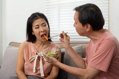 Yaşlı bir çift sıcak bir ev ortamında sağlıklı beslenme alışkanlıkları ve iletişimi teşvik ederek besleyici bir yemek paylaşır..