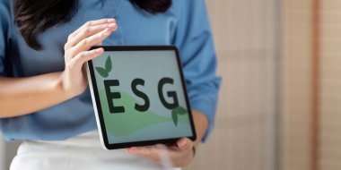 ESG kavramlarını tablette sunan bir iş kadını, tartışmasında sürdürülebilirliği ve kurumsal sorumluluğu vurguladı.