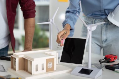 Mühendisler yenilenebilir enerji elementlerinin yer aldığı bir minyatür inşa modeli üzerinde çalışırken sürdürülebilir mimariyi tartıştılar.