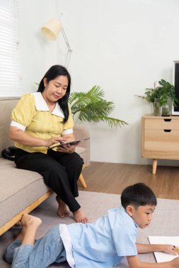 Bir anne ve oğul evde öğrenme aktivitesine girişir, sevgi ve bağlarla dolu destekleyici bir eğitim ortamı oluşturur..