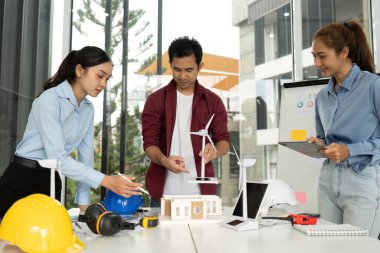 Çeşitli mühendislerden oluşan bir grup eko-dost tasarım stratejileri üzerine beyin fırtınası yapıyor, rüzgar enerjisini yapı modellerine entegre ediyorlar..
