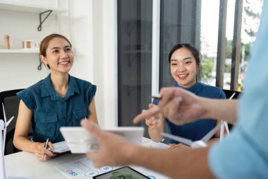 Bir ekip, parlak ve modern bir ofiste sürdürülebilirlik ve ESG girişimleri hakkındaki başarılı fikirlerini kutluyor..
