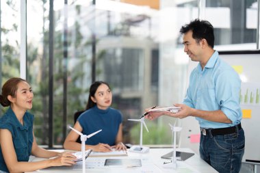 Bir grup profesyonel, çağdaş bir ofis ortamında yenilenebilir enerji fikirleri ve ESG ilkelerini araştırıyor.
