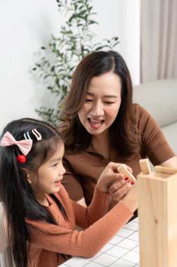 Neşeli bir anne ve kız, Jenga oynarken, yaratıcılığı ve bağlantıyı desteklerken, keyifli bir anı paylaşıyor..