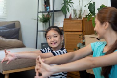 Bir anne ve kız sağlıklı yaşam rutininin tadını çıkarırlar, rahat bir oturma odasında uzanıp, sağlık ve bağlanmayı teşvik ederler..