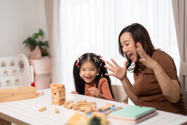 Bir anne ve kızı evde Jenga oynarken neşe ve heyecanı paylaşıyor, neşeli ilişkilerini kutluyorlar..