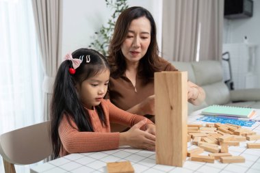 Bir anne ve kızı, Jenga bloklarını istifleyerek, bağ ve yaratıcılıklarını geliştirerek, neşeli bir anın tadını çıkarıyorlar..