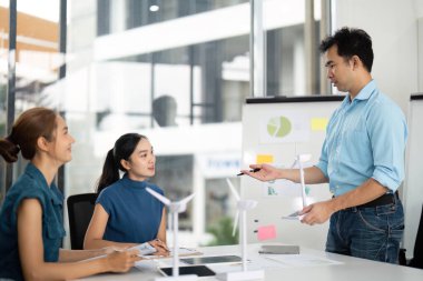 Profesyoneller yenilenebilir enerji stratejileri üzerinde işbirliği yaparak, yenilikçi bir çalışma alanında rüzgar türbini modelleri sergiliyorlar.