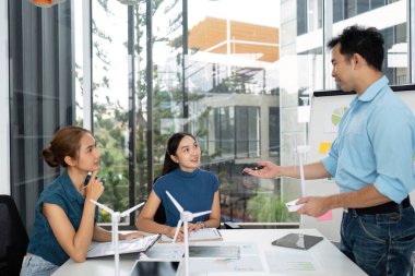 Takım üyeleri, modern bir çalışma alanında görsel yardımlarla ESG hedeflerine odaklanarak, aktif olarak sürdürülebilirlik fikirleri üzerinde beyin fırtınası yapıyorlar..