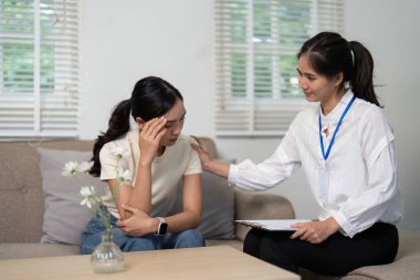 Huzurlu bir terapi odasında, bir psikolog, zihinsel sağlık desteğinin önemini vurgulayarak, bir hastanın endişelerini dikkatle dinlemektedir..
