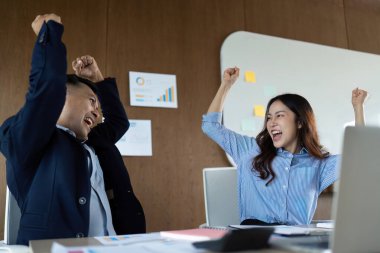 İki iş adamı, başarılarını modern bir ofiste, takım çalışması ve başarının somutlaştırılmış haliyle sevinçle kutluyor..