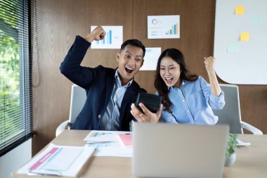 İki profesyonel başarılarını kutlarken, bir dizüstü bilgisayarda olumlu mali sonuçları inceleyerek takım çalışması sergilediler..