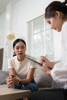 Bir psikolog, sorunlu bir hastayı dikkatle dinler. Sakin bir ortamda terapi seansında ona destek ve rehberlik eder..