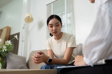 Bir psikolog, zihinsel sağlık tartışmaları için güvenli bir alan sağlayarak dikkatle dinlerken bir hasta endişelerini paylaşıyor..