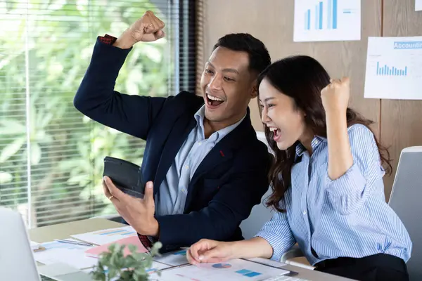 Başarıyı kutlayan iki iş adamı bir tablette olumlu sonuçlar alırken, takım çalışması ve başarıyı somutlaştırıyor.