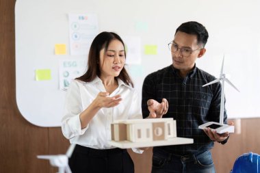 Profesyoneller sürdürülebilir tasarım modelleri sergiliyor, ofis ortamında yenilik ve takım çalışmalarını vurguluyorlar.