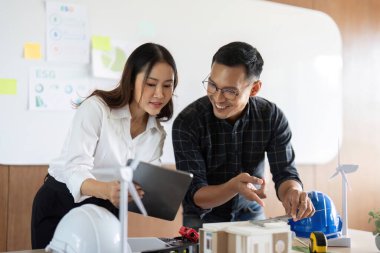 Mühendisler bir ofis ortamında sürdürülebilir tasarım kavramları, sergilenen modeller ve teknoloji üzerinde işbirliği yaparlar..