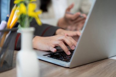 İki meslektaş, bir dizüstü bilgisayar kullanırken proje detaylarına odaklanarak, modern bir çalışma alanında verimli bir tartışmaya giriştiler..