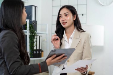 İki iş adamı proje detayları hakkında anlamlı bir konuşma yapıyor, kurumsal bir ortamda etkili iletişimi vurguluyorlar..