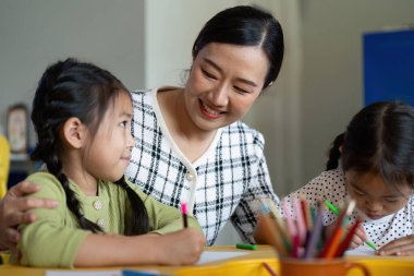 Bir öğretmen, yaratıcı bir çizim seansından zevk alan genç öğrencilerle içtenlikle iletişim kurarak öğrenmeye olan sevgisini arttırır..