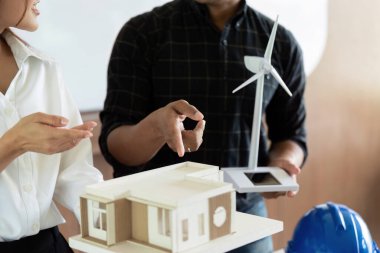 İşbirlikçi ofis ortamında çevre dostu bina tasarımları ve rüzgar türbini modelleri sunan mühendisler, sürdürülebilirliğe odaklanıyorlar..