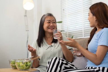 Bir anne ve kız, sağlıklı atıştırmalıkların ve içkilerin tadını çıkarırken, mutluluğu ve bağlantıyı vurgulayarak keyifli bir anı paylaşırlar..