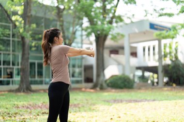 Bir kadın, sakin bir açık hava ortamında esneme egzersizleri yapar. Doğal ortamdaki sağlık ve fiziksel uygunluğu teşvik eder..