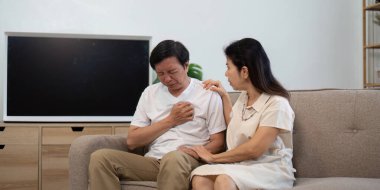 Yaşlı bir adam, partneri kendisini rahatlatırken rahatsızlık belirtileri gösterir. Sağlığın ve duygusal desteğin önemini vurgular..