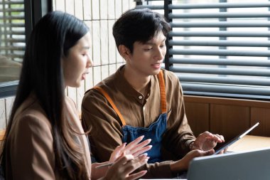 Genç bir erkek ve kadın, canlı bir çalışma alanında takım çalışması sergileyen bir tableti incelerken aynı görüşü paylaşıyorlar..