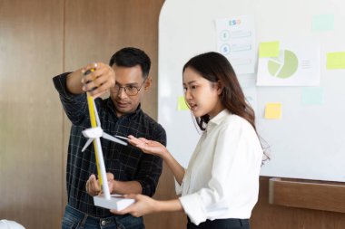 Mühendisler, sürdürülebilir enerji çözümleri ve çevre tasarımı uygulamasını tartışarak bir rüzgar türbini modelini analiz ediyorlar..