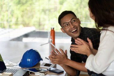 Başarılı sürdürülebilir bir proje için sevinç ve coşku ifade eden bir mühendis, takım çalışmasını ve işbirliğini vurguluyor.