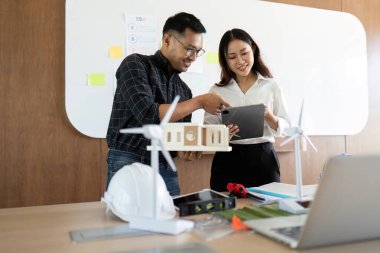 Sürdürülebilir bir inşaat projesinin planlarını inceleyen mühendisler, takım çalışması ve yenilikçi çözümler sergiliyor.