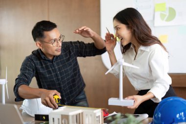 Mühendisler, sürdürülebilir enerji projeleri ve çevresel etki için kesin özellikler üzerinde işbirliği yaparak bir rüzgar türbini modelini ölçüyor.