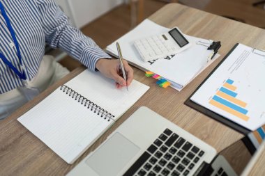 İş belgeleriyle çevrili profesyonel bir defterdeki yakın plan bir çalışma ortamında etkili not alma görüntüsü.