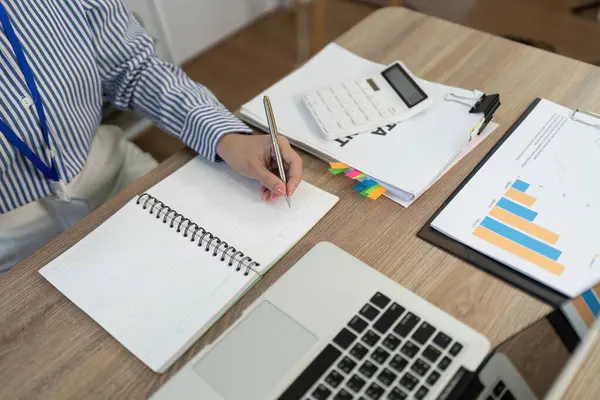 İş belgeleriyle çevrili profesyonel bir defterdeki yakın plan bir çalışma ortamında etkili not alma görüntüsü.