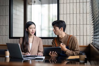 Çağdaş bir çalışma alanındaki belgeleri ve dijital içeriği inceleyen bir erkek ve kadın odaklı bir sohbete girişiyor..