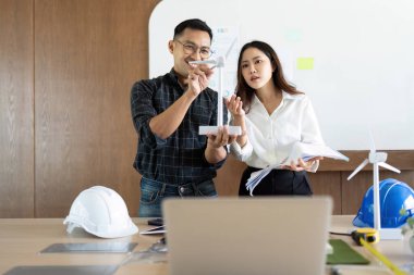 Mühendisler çevre dostu bina kavramları sergiliyor ve ortak bir çalışma alanında rüzgar türbini modellerini tartışıyorlar..