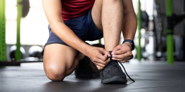 Bağcıklarını bağlamak için kendini adamış bir birey, hazırlanma ve sağlığa olan bağlılığını vurgulayarak diz çöker..