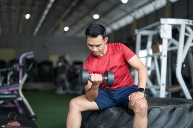 Kendini işine adamış bir adam spor salonunda halterli bir biseps kıvırıyor. Güç antrenmanına ve sağlığına odaklanıyor..