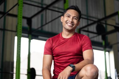 Neşeli bir sporcu spor salonunda poz verir, kendine güveni ve sağlık ve zindeliğe bağlılığı gösterir..