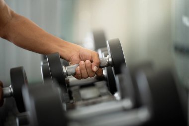 Dambılı kavrayan bir bireyin yakın plan görüntüsü, güç eğitimi ve sağlığa odaklanılmasını vurguluyor.