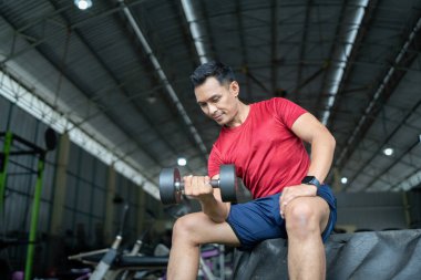 Kendini işine adamış bir adam spor salonunda halterli bir biseps kıvırıyor. Güç antrenmanına ve sağlığına odaklanıyor..
