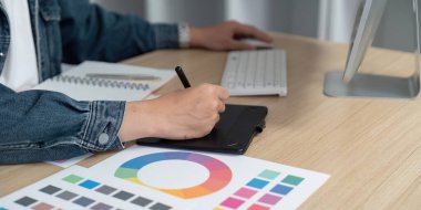 Bir tasarımcı aktif olarak bir grafik tablet üzerinde çizim yapar, renk paletlerini keşfeder ve modern çalışma alanlarında yaratıcılığı artırır.